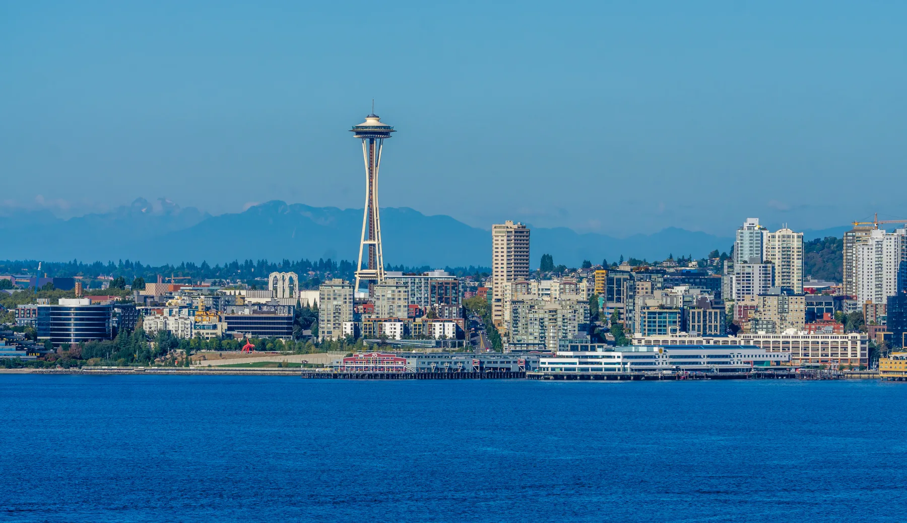 Seattle skyline across the water with the Space Needle and mountains in the distance